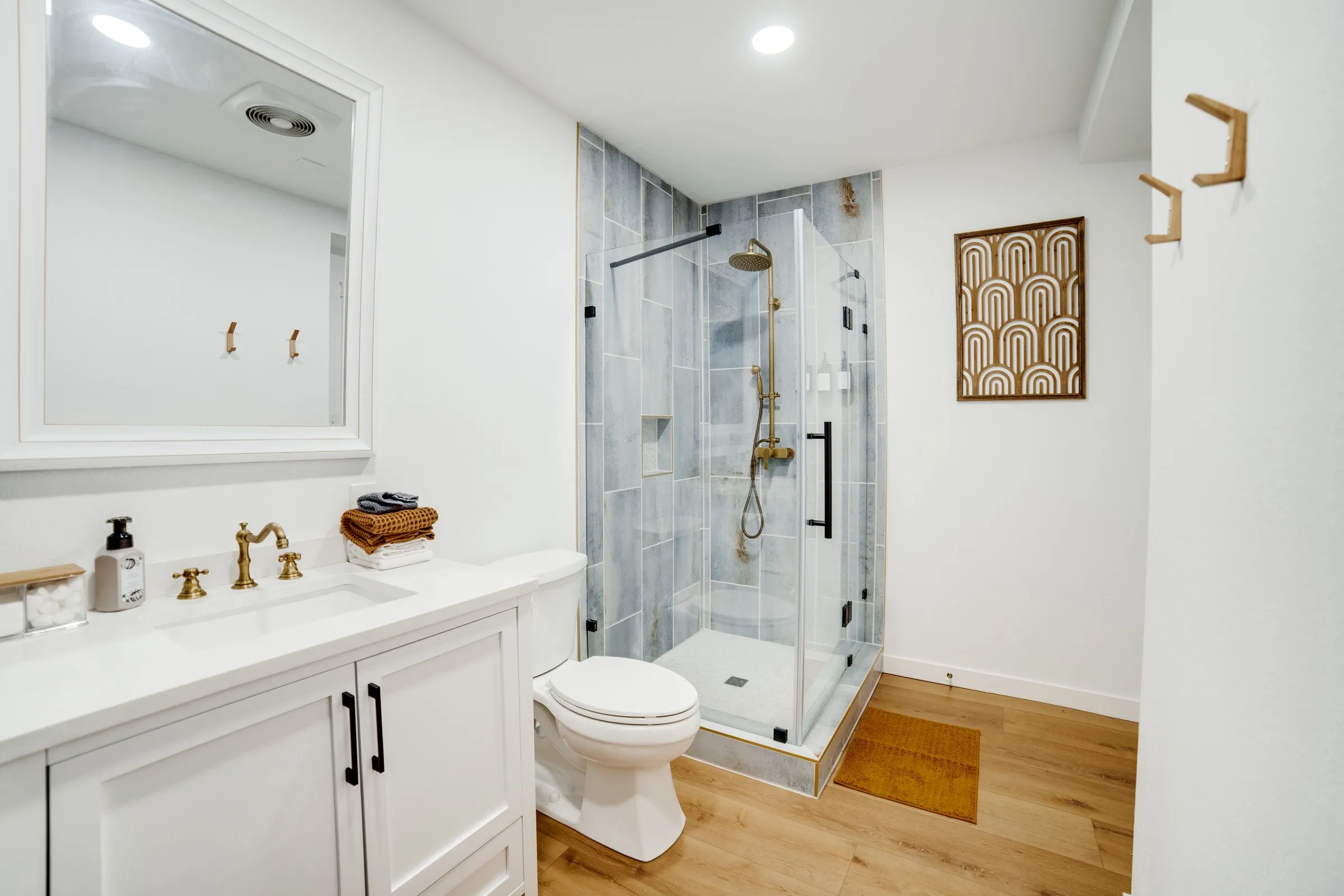 Bathroom with glass-enclosed shower, brass faucets and white vanity