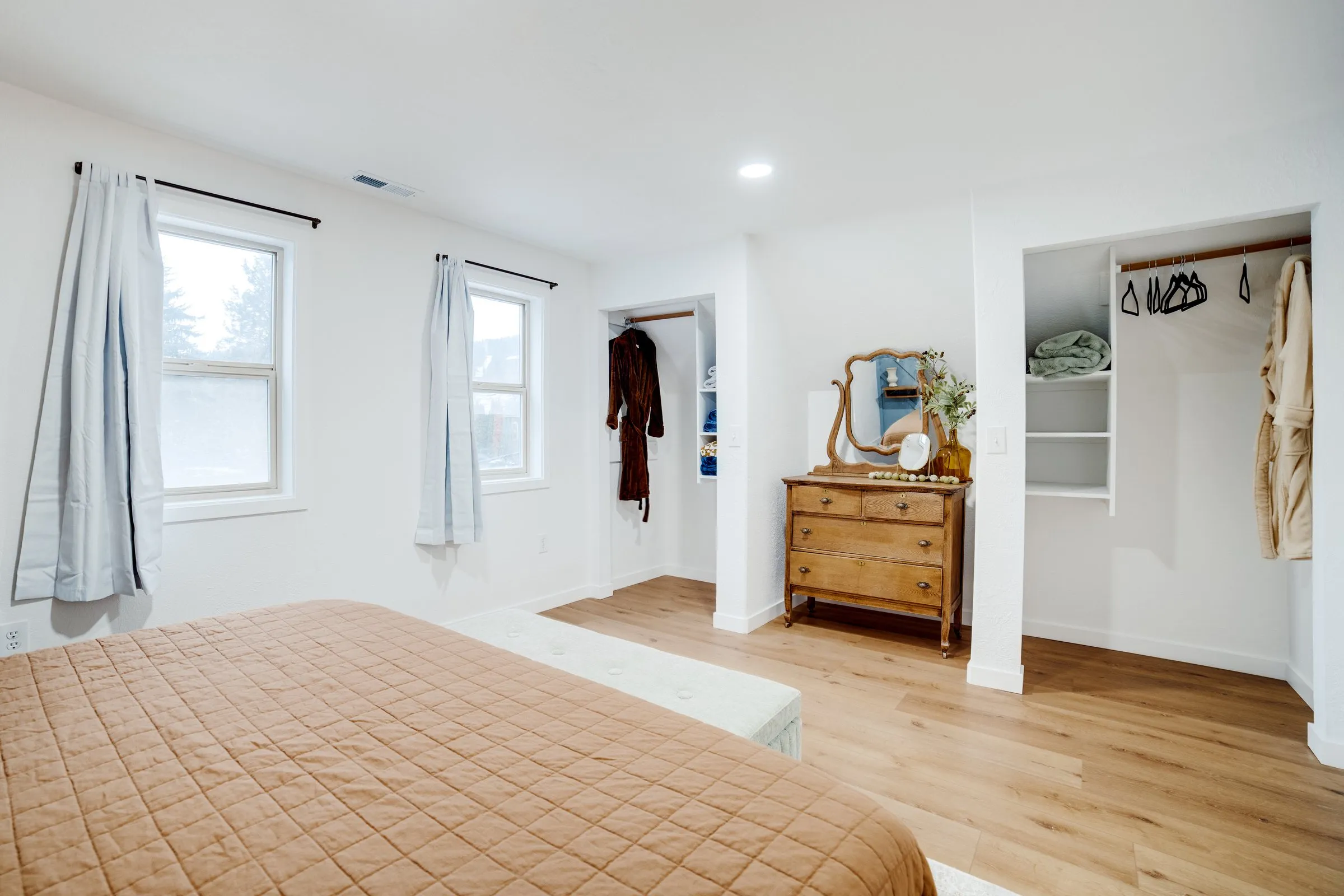 Bedroom with vintage mirrored dresser and robes in the closet
