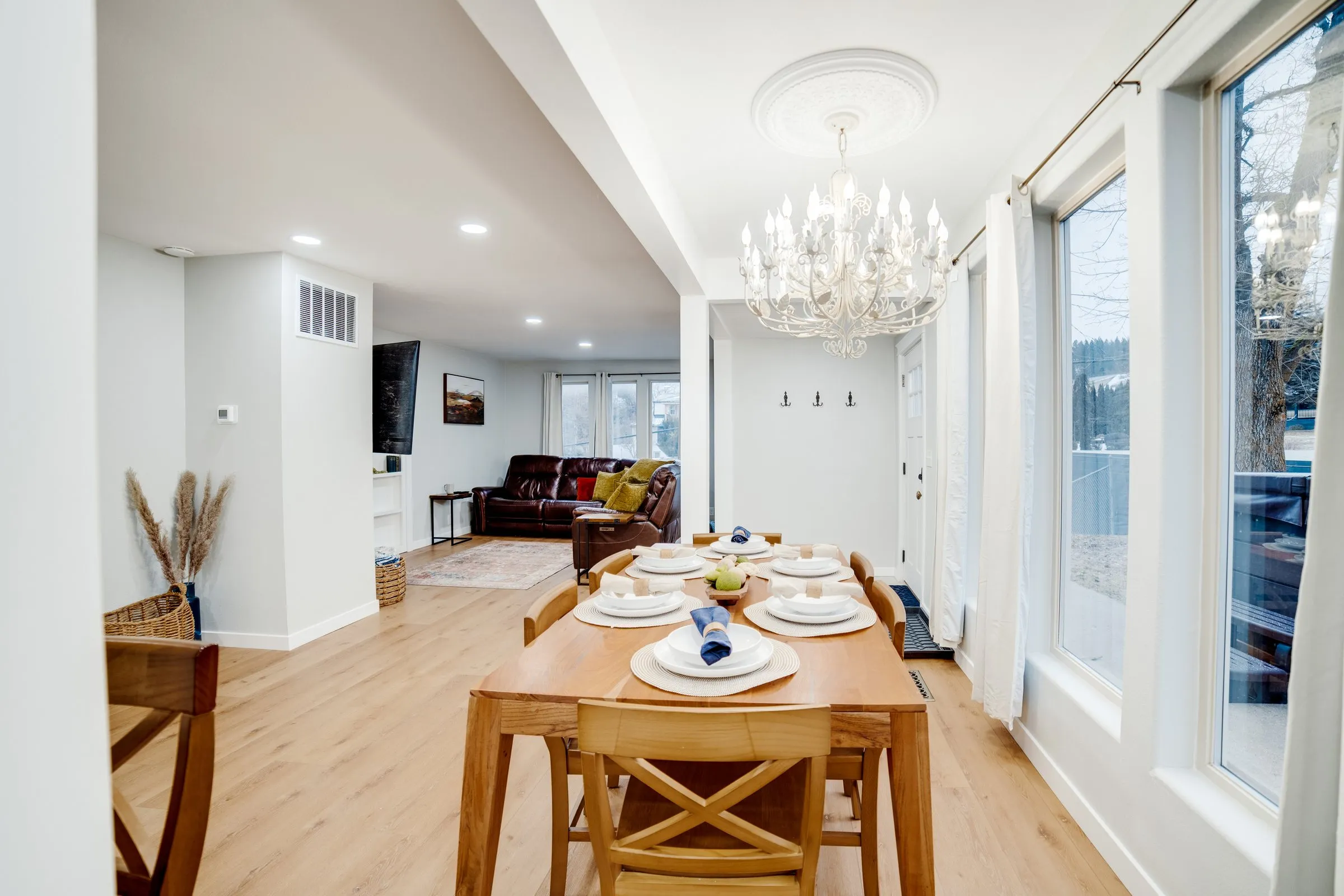 Dining room with chandelier, large windows and view into the living room