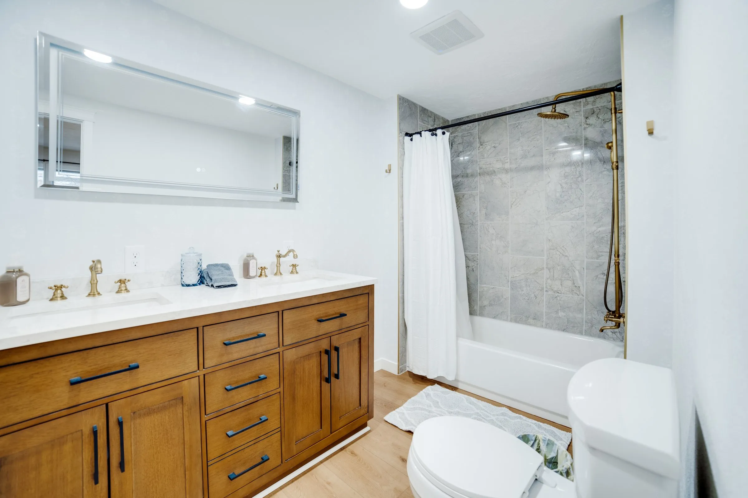 Bathroom with double vanity, brass faucets and tub-shower combo