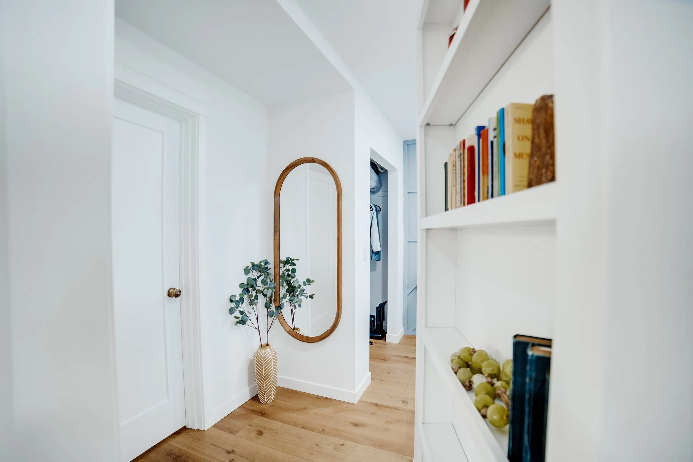 Hallway with built-in bookshelves and an oval wood mirror