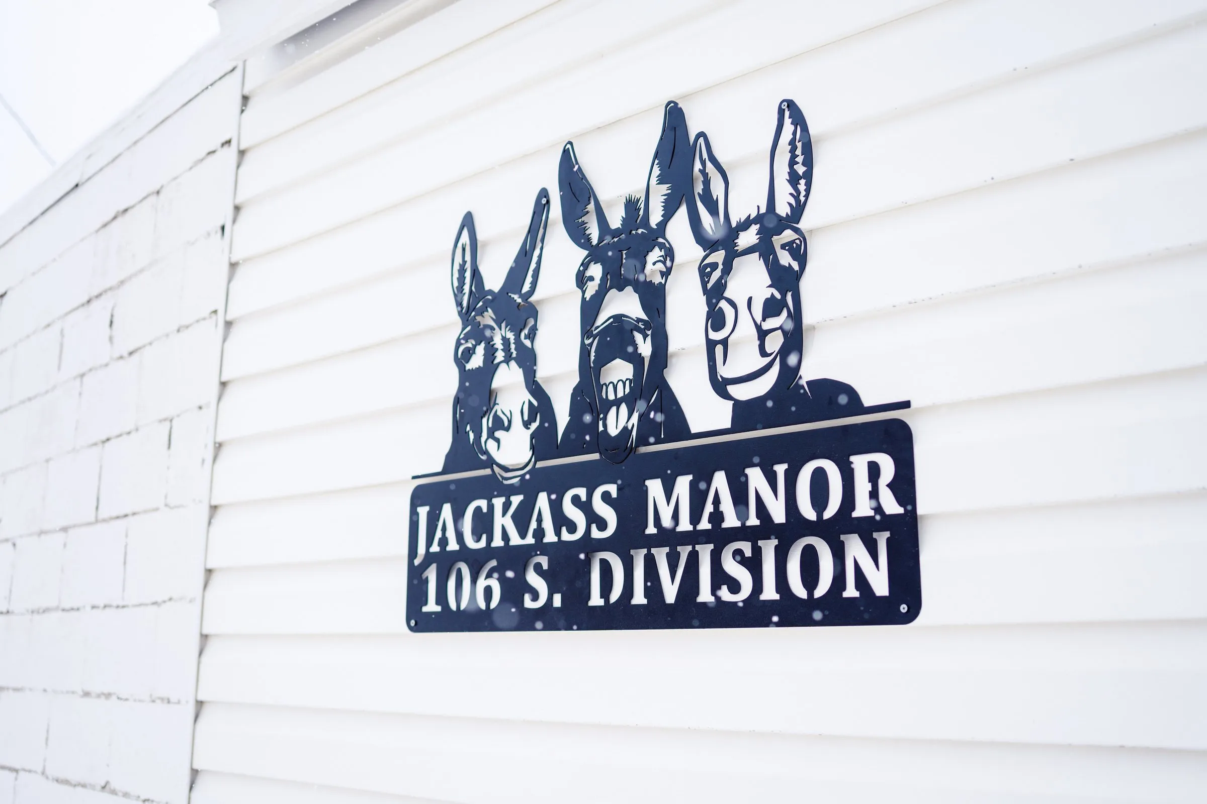 Three-donkey metal sign on the siding of Jackass Manor in Kellogg, Idaho