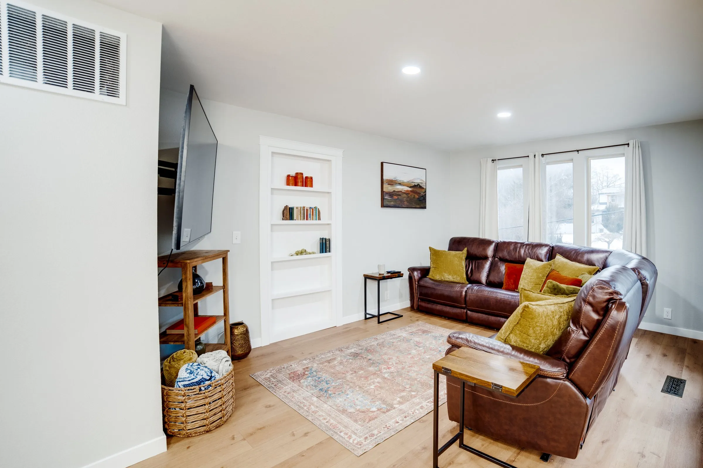 Cozy living room with a large wall-mounted TV, built-in bookshelves and leather recliners