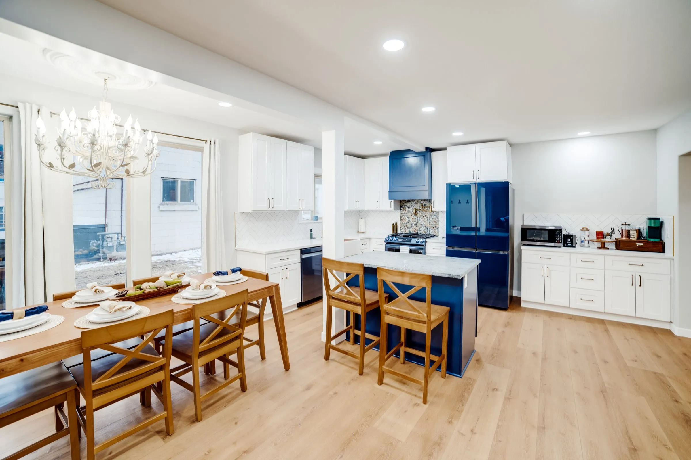 Open kitchen with navy French-door refrigerator, island seating and dining table